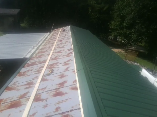 Old rusted panels beside newly installed green metal roofing — Wind Damage Roof Repair by Roofing Brothers in Broken Arrow