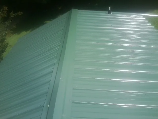 New green metal panels meeting at the ridge of a roof — Flat Roof Repair work by our crew in Broken Arrow