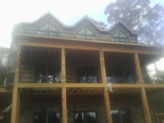 Dormers and porch framing on a large log home under construction — Roof Coating work by our crew in Broken Arrow