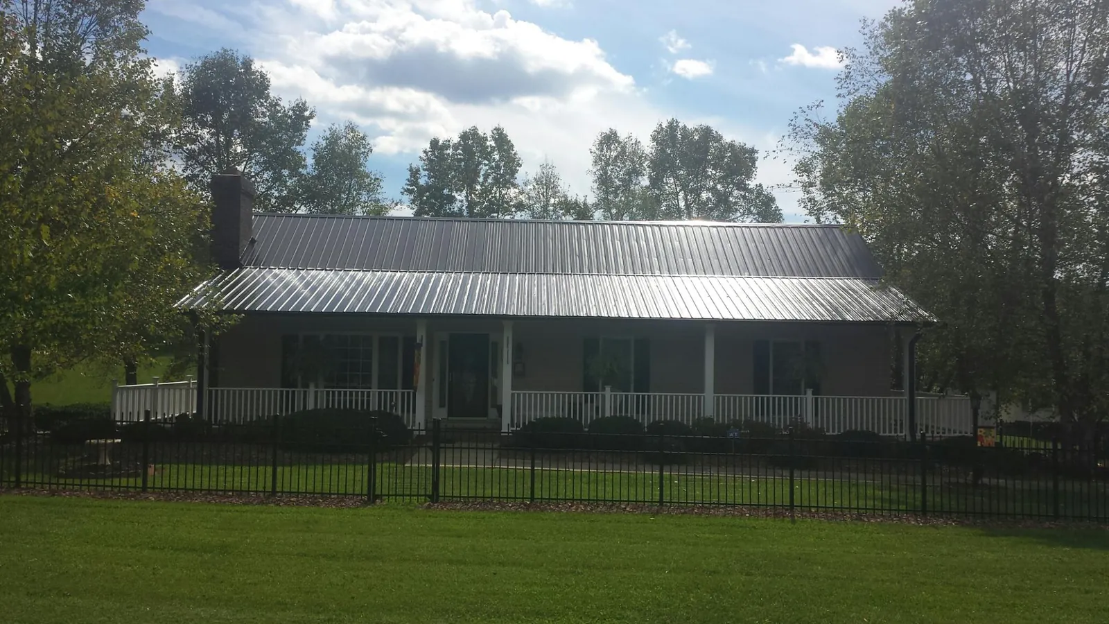 Gray metal roof on a brick ranch with a full width front porch — Gutter Guard Installation work by our crew in Broken Arrow